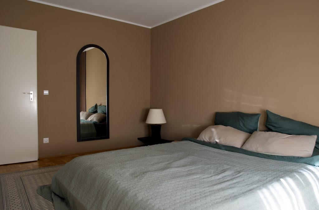 Erdendes Schlafzimmer in Beige- und Grüntönen mit dunklem Holz und einem tiefen japanischen Bett.